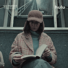 a woman sitting on a train reading a book with the words nine perfect strangers below her