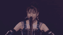 a woman singing into a microphone with her hands outstretched