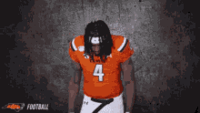 a kansas football player wearing number 4 stands with his hands in his pockets