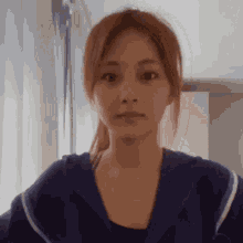 a close up of a woman wearing a blue hoodie and looking at the camera .