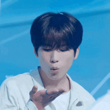 a young man blowing a kiss with a blue background