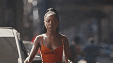 a woman in an orange top is walking down a street