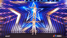 a man and a woman are standing on each other 's shoulders on a stage with a nbc logo behind them