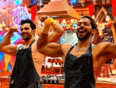two men wearing aprons are flexing their muscles