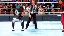 a wrestler is standing in the middle of a ring with a referee standing behind him .