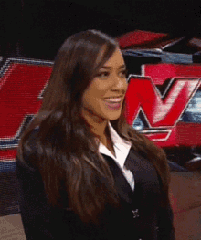 a woman in a suit is smiling in front of a large red n