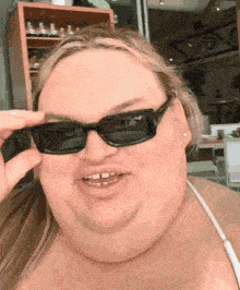 a woman wearing sunglasses looks at the camera
