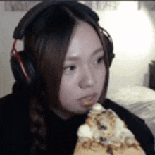 a woman wearing headphones is eating a pizza .