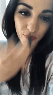 a close up of a woman 's face with her finger on her mouth
