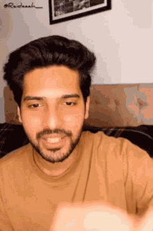 a man with a beard wearing a tan shirt is smiling