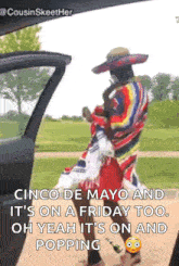 a man in a sombrero is standing next to a car with the door open .