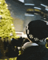 a person wearing a black hat with snowflakes on it is looking at a christmas tree