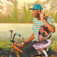 a man is holding a little girl who is riding a bike