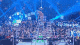 a wrestler is standing on a ladder in front of a crowd at a wrestling event