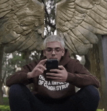 a man wearing a hoodie that says " that 's awful of cough syrup " looks at his cell phone