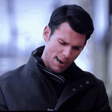 a man wearing a black jacket has a small bug sticking out of his mouth