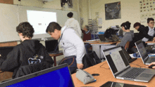 a man wearing a hoodie that says x on it is standing in front of a laptop