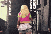 a woman in a pink vest and white skirt is dancing on a stage