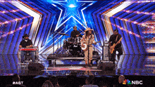 a band is performing on a stage with a nbc logo on the bottom