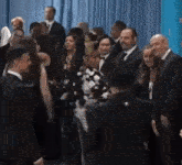 a group of people standing in front of a blue curtain .
