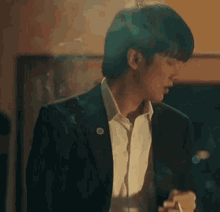 a man in a suit and white shirt is smoking a cigarette in a dark room .