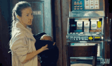 a woman holding a baby in front of a slot machine that says this machine accepts 15 10 10 10 bills