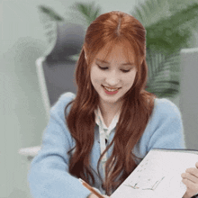 a woman with red hair is smiling while holding a notebook