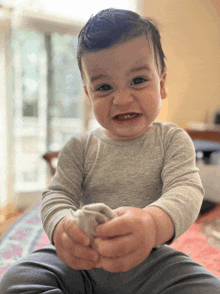 a baby is sitting on a bed and smiling