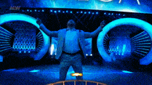 a man in a suit is standing on a stage with his arms outstretched in front of a aew logo .