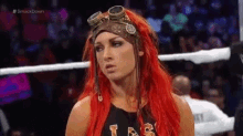 a woman with red hair and goggles is standing in a ring .