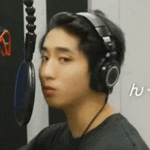 a man wearing headphones is sitting in front of a microphone in a recording studio .