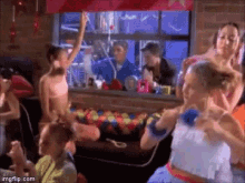 a group of young girls are dancing in front of a window .