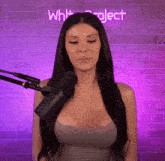 a woman stands in front of a microphone in front of a purple wall with the word whit project on it