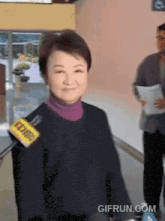 a woman wearing a black sweater with a yellow sticker that says ' gifrun.com ' on it