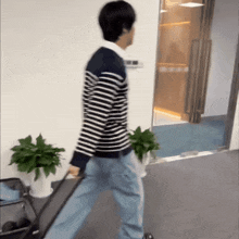 a man in a striped sweater is pulling a suitcase down a hallway