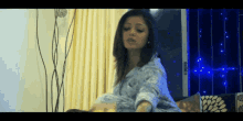 a woman is laying on a bed in front of a window with blue lights behind her