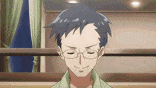 a man with glasses and a green shirt is smiling with his eyes closed