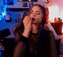 a woman sitting in a chair with a microphone on her head eating something