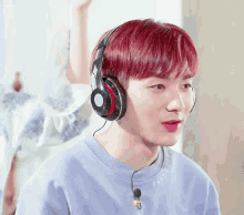 a young man with red hair wearing headphones and a purple shirt that says paris