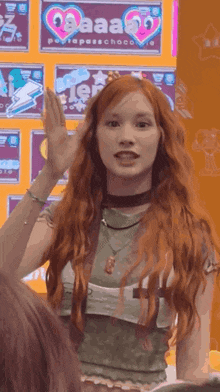 a woman with red hair stands in front of a sign that says aaa on it