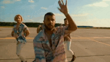 a group of men are dancing on a runway and one of them is waving .