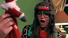 a woman wearing glasses and a hat with a shark on it looks surprised