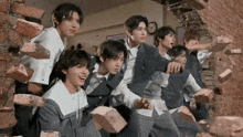 a group of young men are standing in front of a brick wall holding bricks .