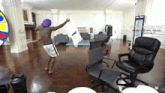 a man in a purple hat is holding a pillow that says one in a living room