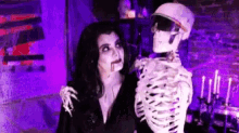 a woman in a vampire costume is hugging a skeleton in a dark room .