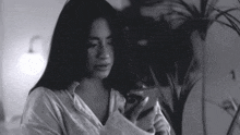 a black and white photo of a woman using a cell phone