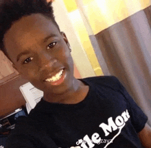 a young man wearing a black t-shirt that says little monk is smiling for the camera .
