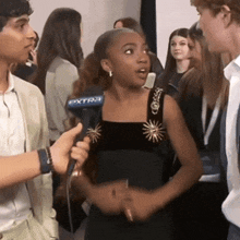 a woman in a black dress is being interviewed by a man wearing an extra microphone