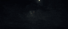 a group of people are standing in a dark room with a light coming out of it .