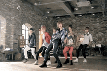 a group of young men dancing in a room with a brick wall